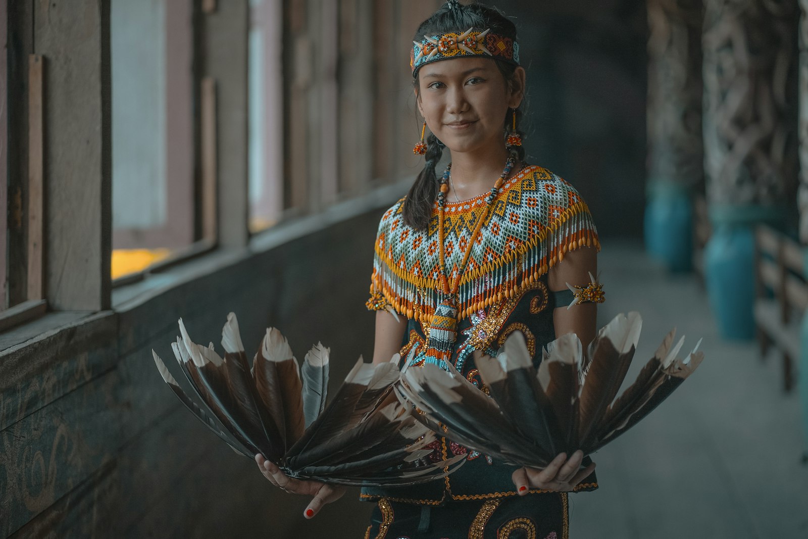 A woman in a colorful dress holding a bunch of feathers
