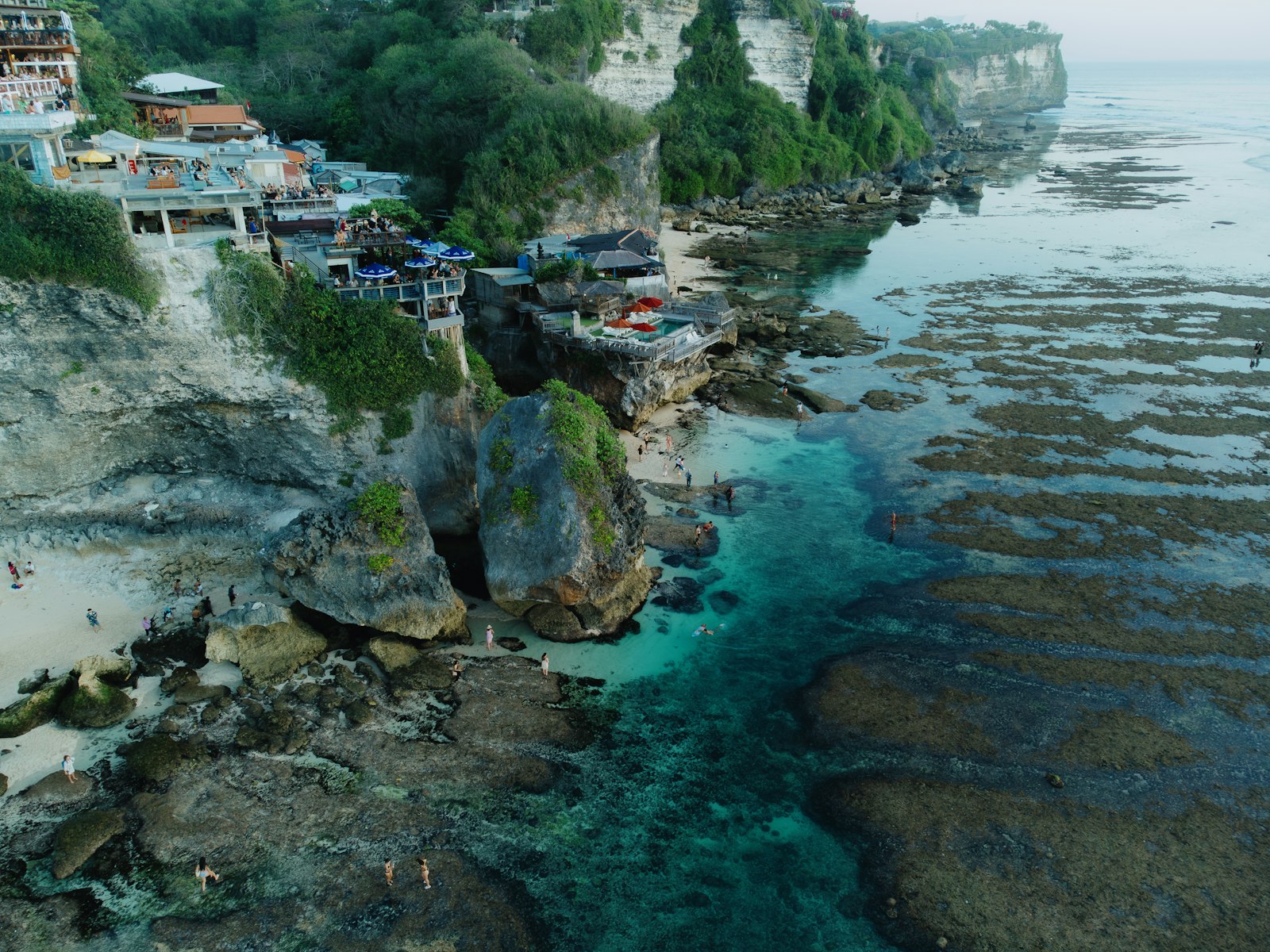 An aerial view of a beach with houses on the cliff