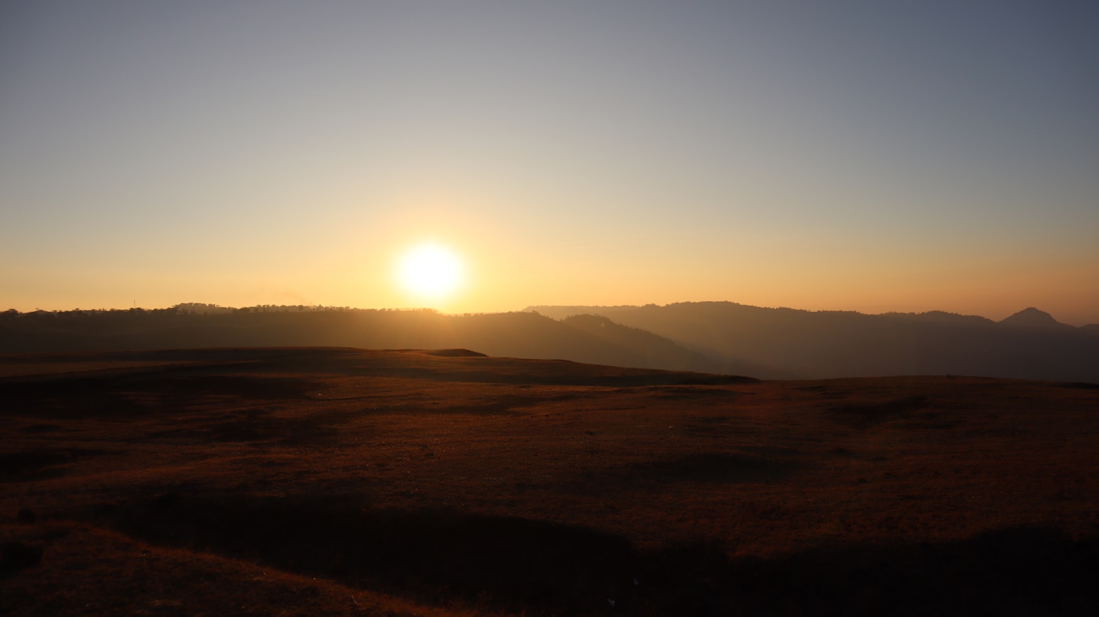 the sun is setting over a mountain range